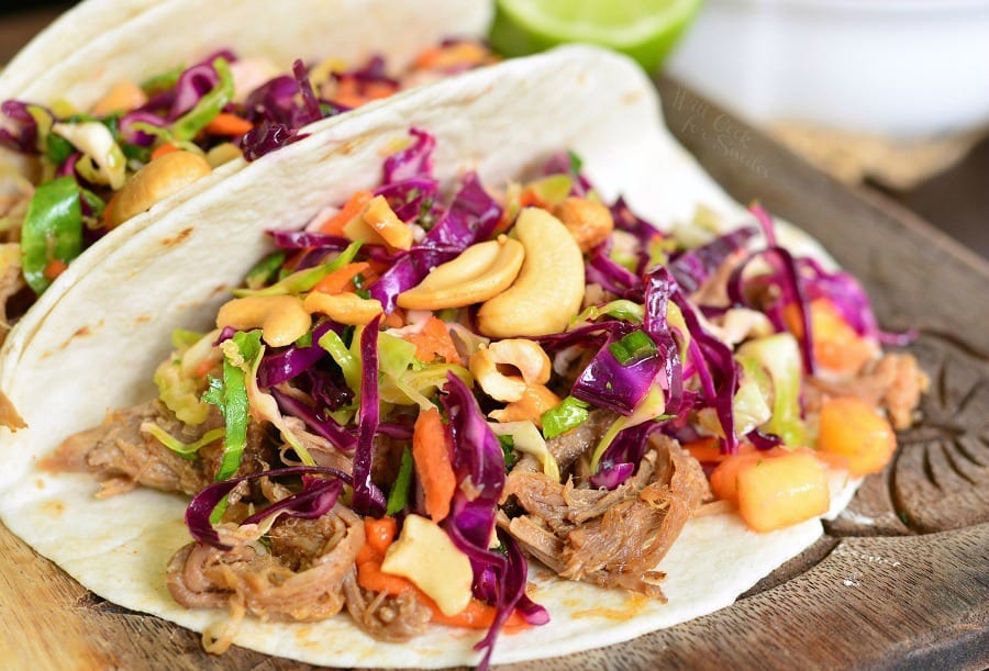 two Pulled Pork Tacos with Tropical Slaw on a cutting board 