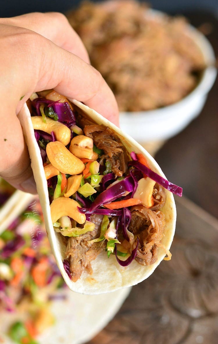 Holding a pulled Pork Tacos with Tropical Slaw.