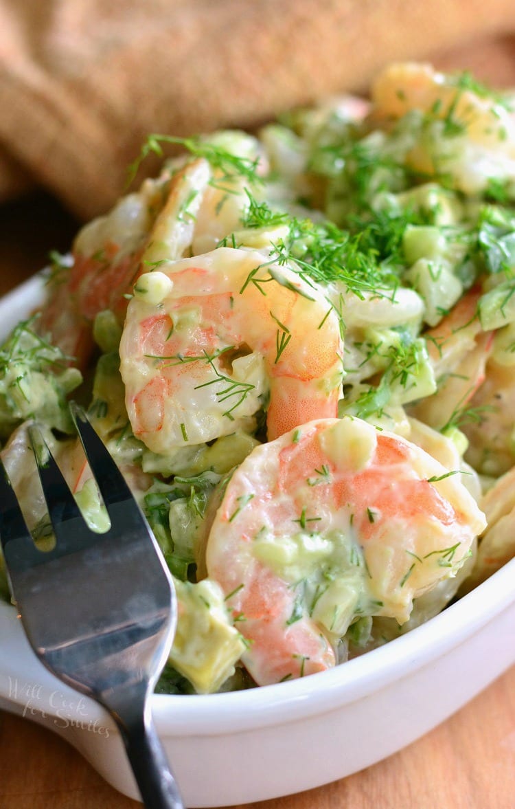 side view of the salad in a bowl with a fork in the bowl and brown towel next to it