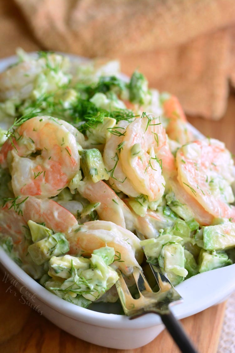 fork pulling out one of the shrimp from a bowl of the mixed salad