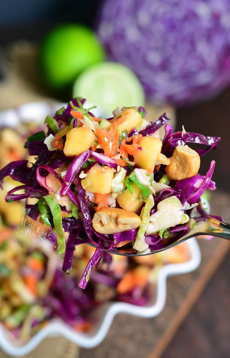 Tropical Slaw on a spoon and in a white serving bowl with a lime in the background 