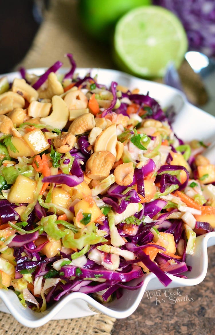 Tropical Slaw in a white serving bowl with a lime in the background 