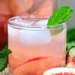 mint peach spritzer in a glass with a mint leaf as garnish.