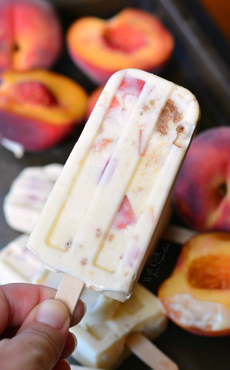 Holding Peach Cobbler Pudding Pop with peaches in the background 