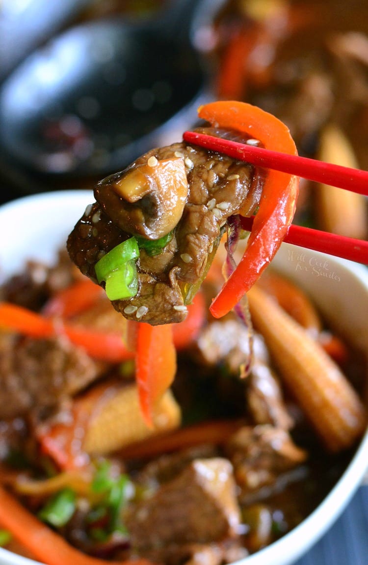 lifting some of the Sesame Steak Stir Fry with chop sticks out of the bowl 