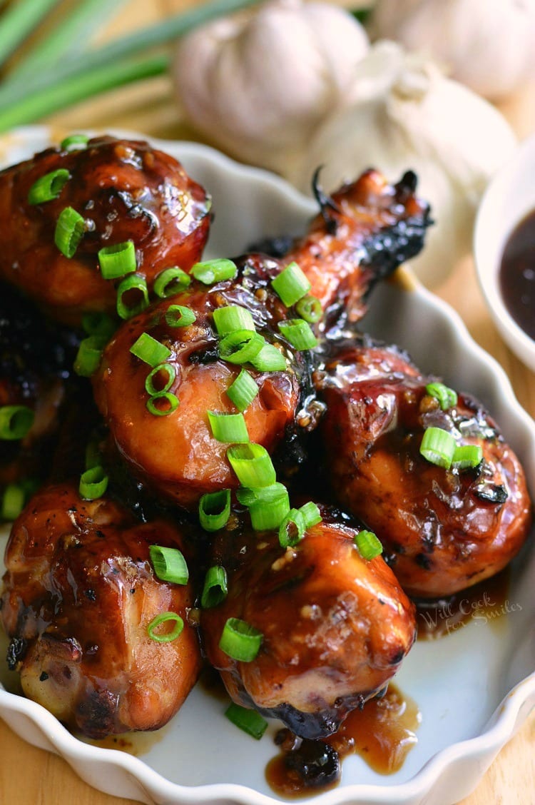 several grilled chicken drumsticks in sweet garlic glaze topped with green onions.