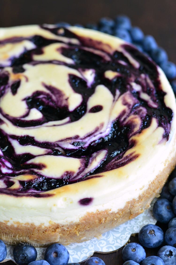 White Chocolate Blueberry Cheesecake on a plate with blueberries around it 