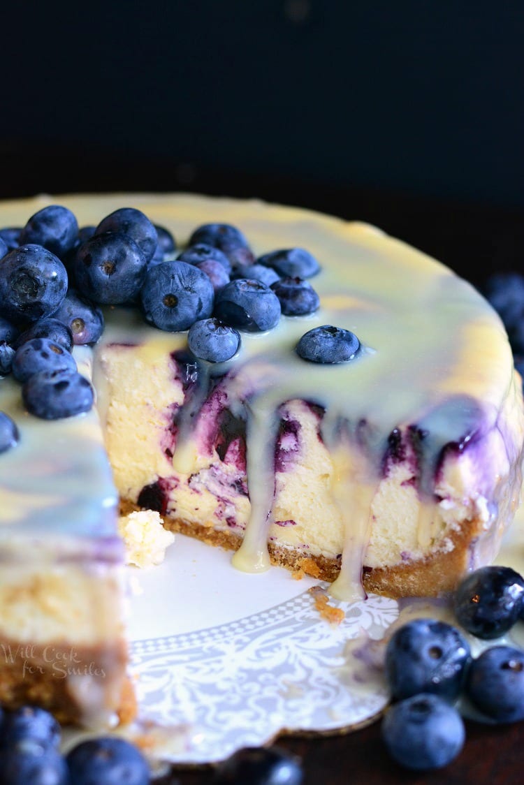 white chocolate cheesecake with slice out of it and blueberries on top.