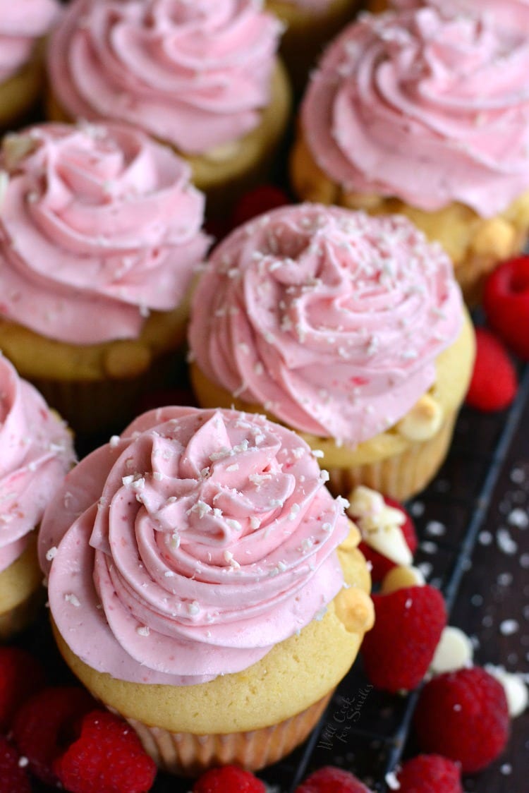 up close above photo of cupcakes with pink raspberry cream frosting on top.