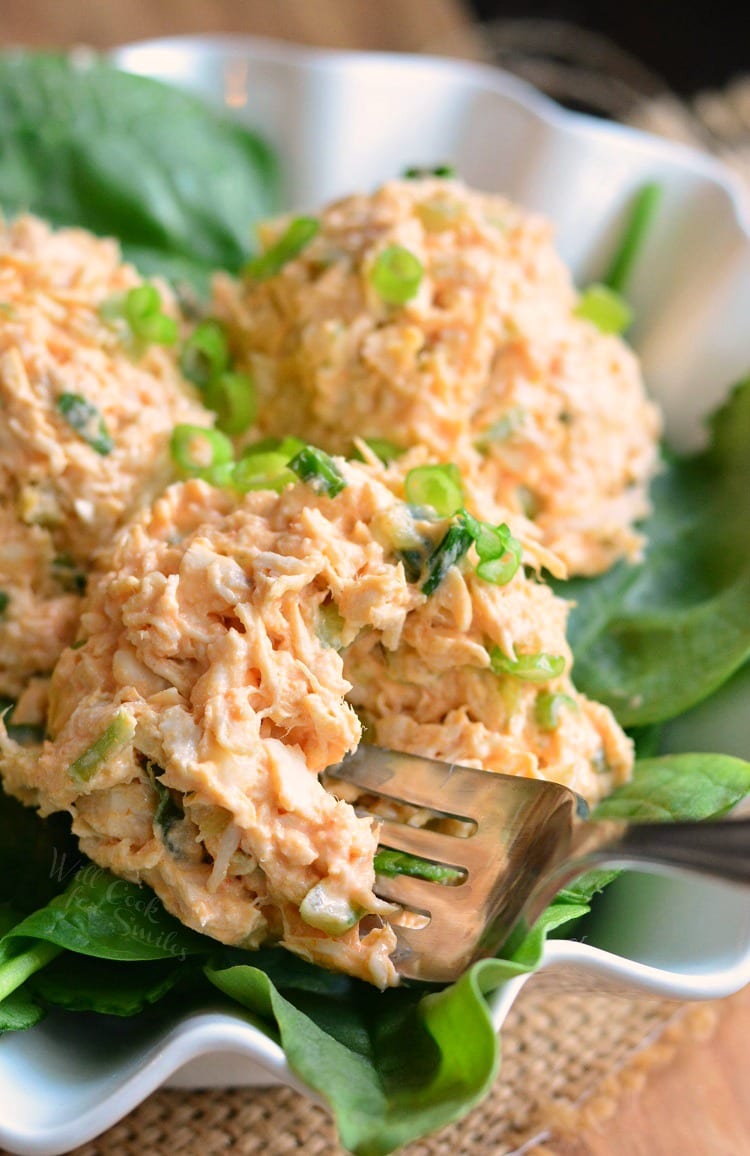 Zesty Buffalo Chicken Salad on a bed of lettuce in a white bowl with a fork in the salad 