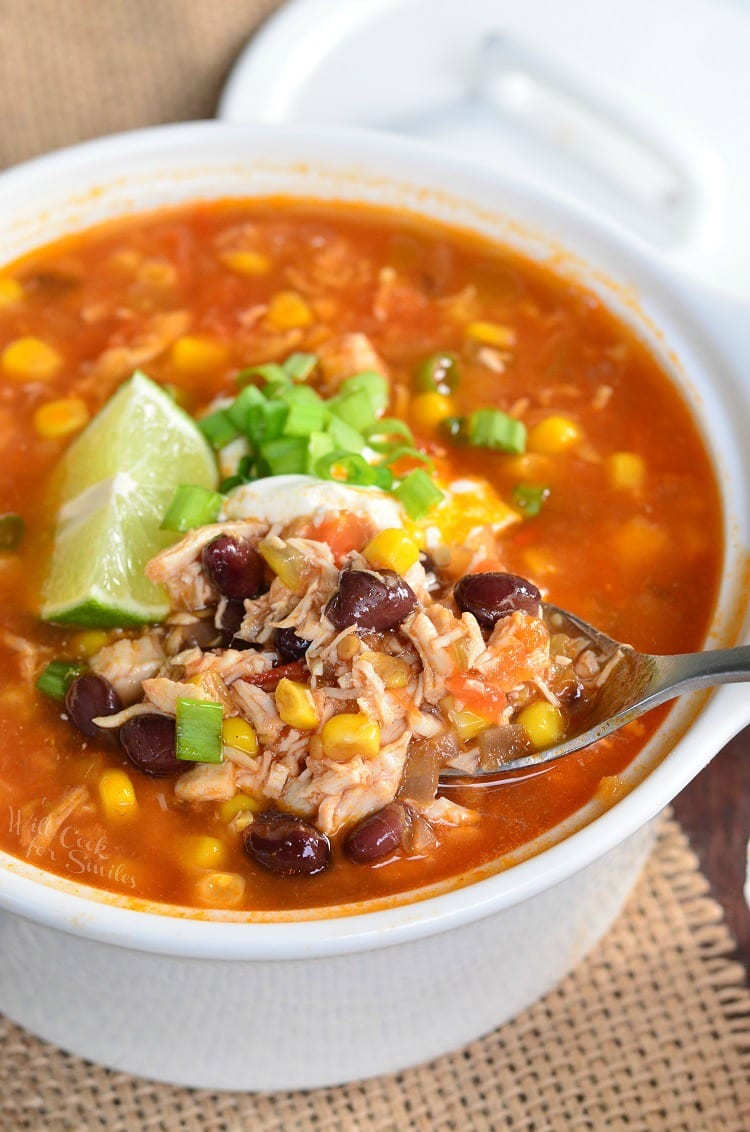 Chicken Tortilla Soup in a bowl with a lemon wedge on top and sour cream spoon 