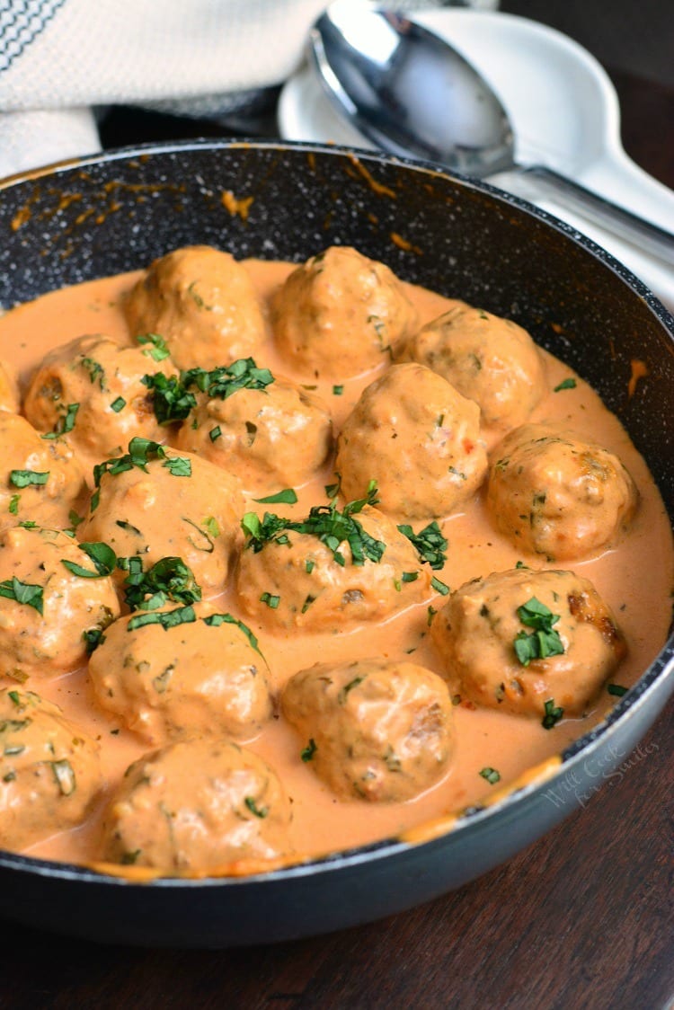 several tender and juicy beef and pork meatballs in creamy tomato sauce in a cooking pan.