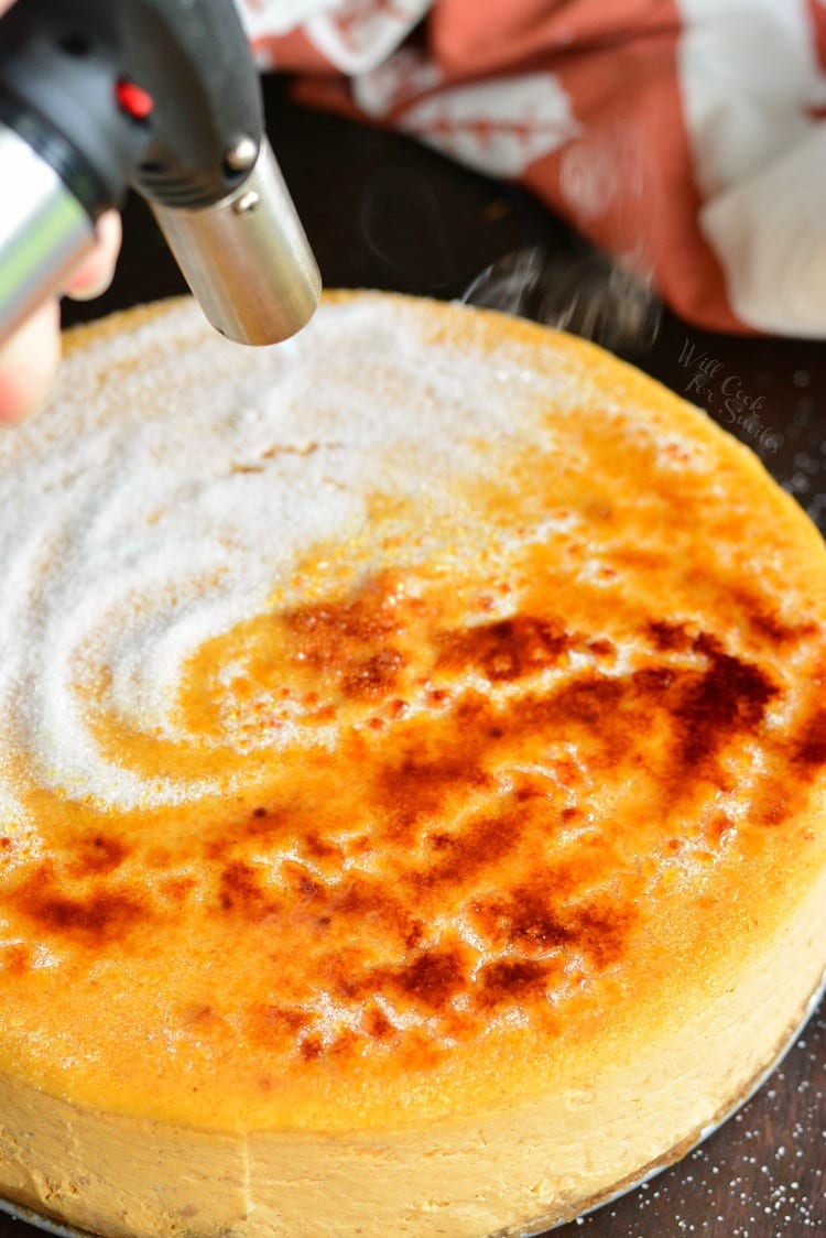 Using a torch, melting the sugar on the cheessecake to golden brown as it forms a crispy top