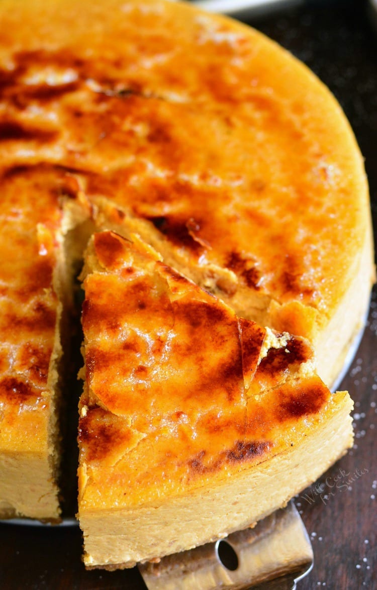 Cutting a piece of Creme Brulee Pumpkin Cheesecake on a wood table 