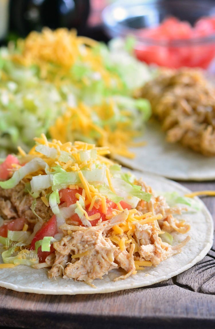 Pulled chicken taco on a tortilla with lettuce, tomato, and cheese.