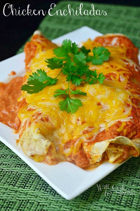 chicken enchiladas on a white plate with cilantro on top  on a table with a green placemat 