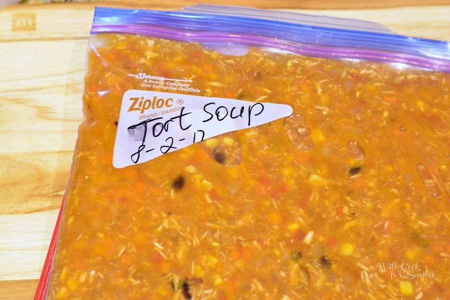 Chicken Tortilla Soup in a freezer bag on a wood cutting board 