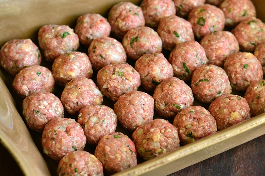 uncooked meatballs in a tan casserole dish 