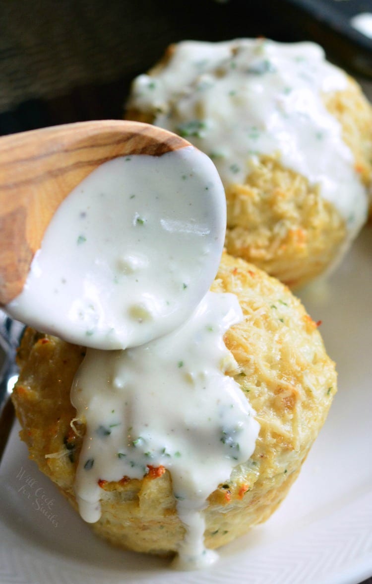 pouring sauce over Garlic Parmesan Chicken Mini Meatloaves with a wooden spoon on a plate 