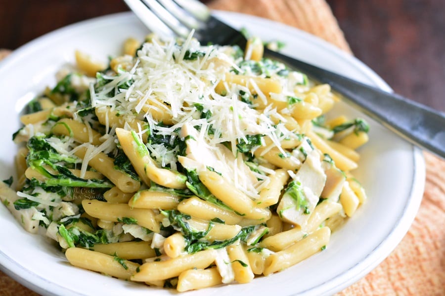 Garlic and Spinach Alfredo Chicken Pasta with cheese on top and bowl with a fork 