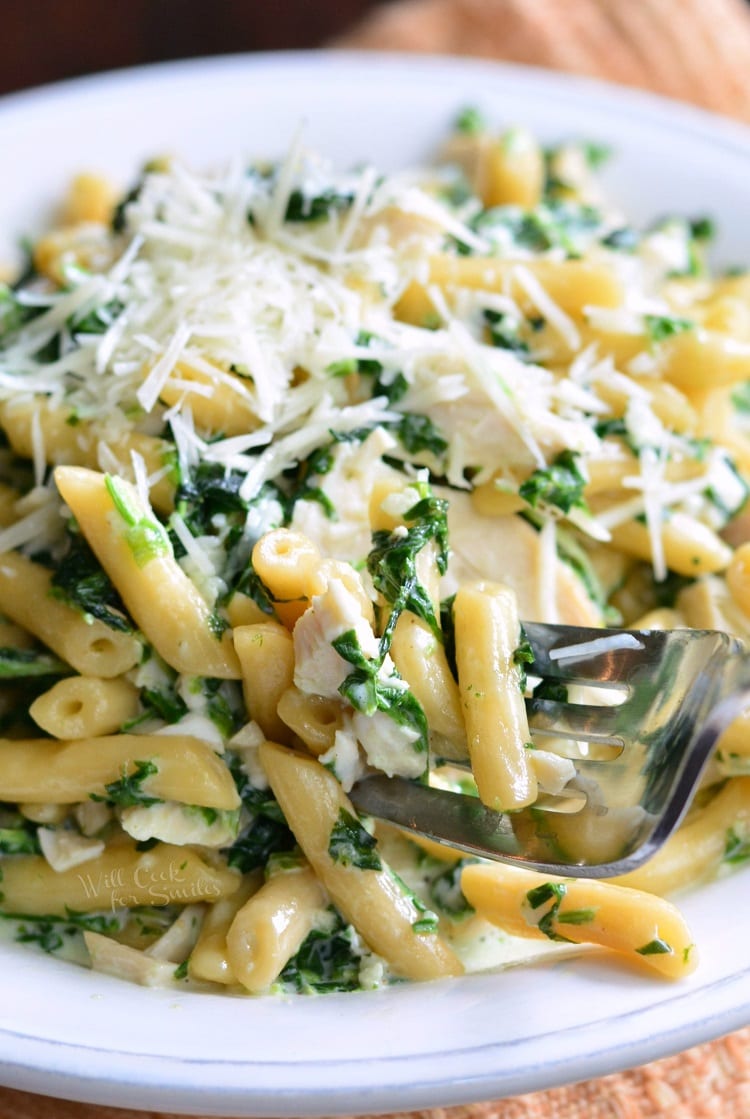 Garlic and Spinach Alfredo Chicken Pasta with cheese on top and bowl with a fork 