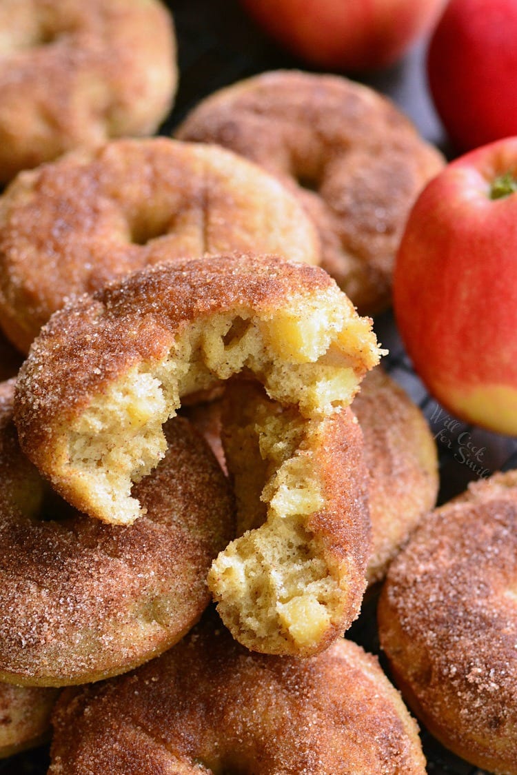 Apple Pie Baked Doughnuts one cut in half on a cooling rack with apples in the background 