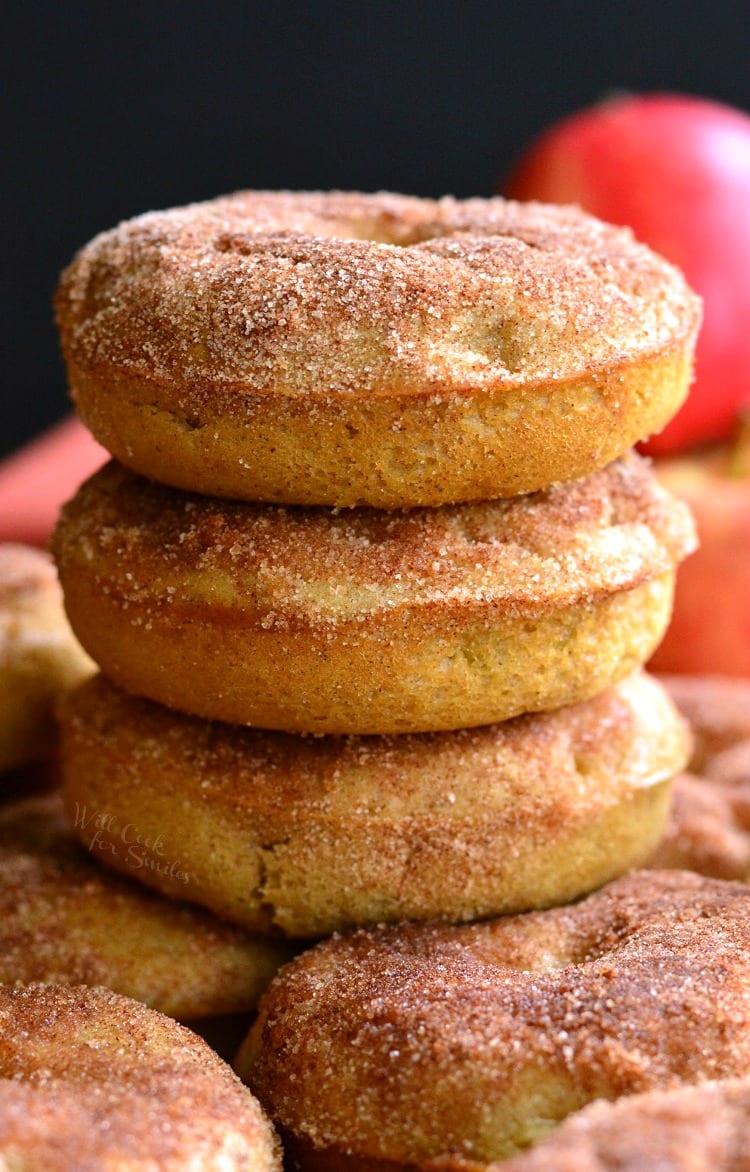 Apple Pie Baked Doughnuts stacked on a cutting board with apples in the background 