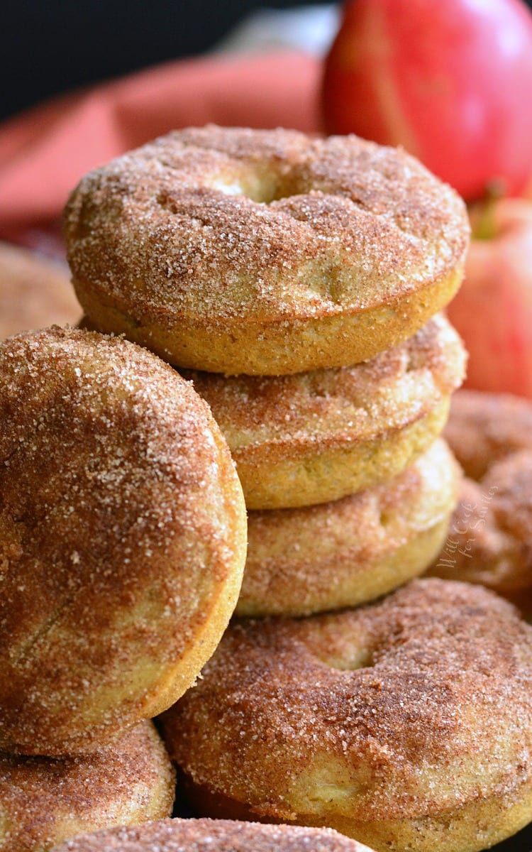 Apple Pie Baked Doughnuts stacked on a wood cutting board with apples in the background 