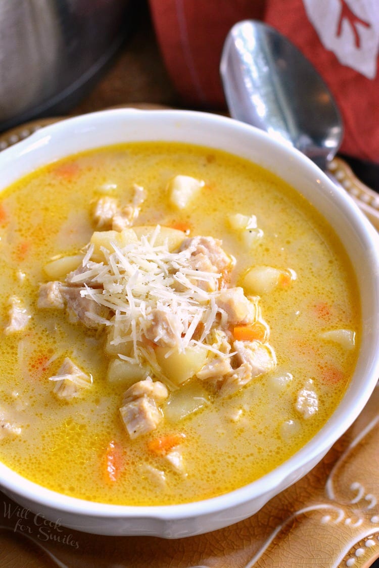 Creamy, Chunky Turkey Potato Soup with cheese on top in a bowl that is on a brown plate with a spoon 