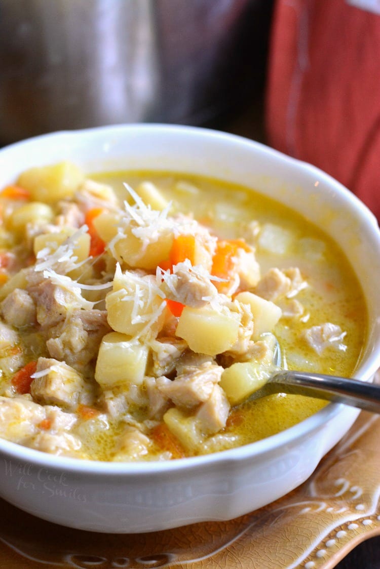 Creamy, Chunky Turkey Potato Soup with cheese on top in a bowl with a spoon that is on a brown plate 