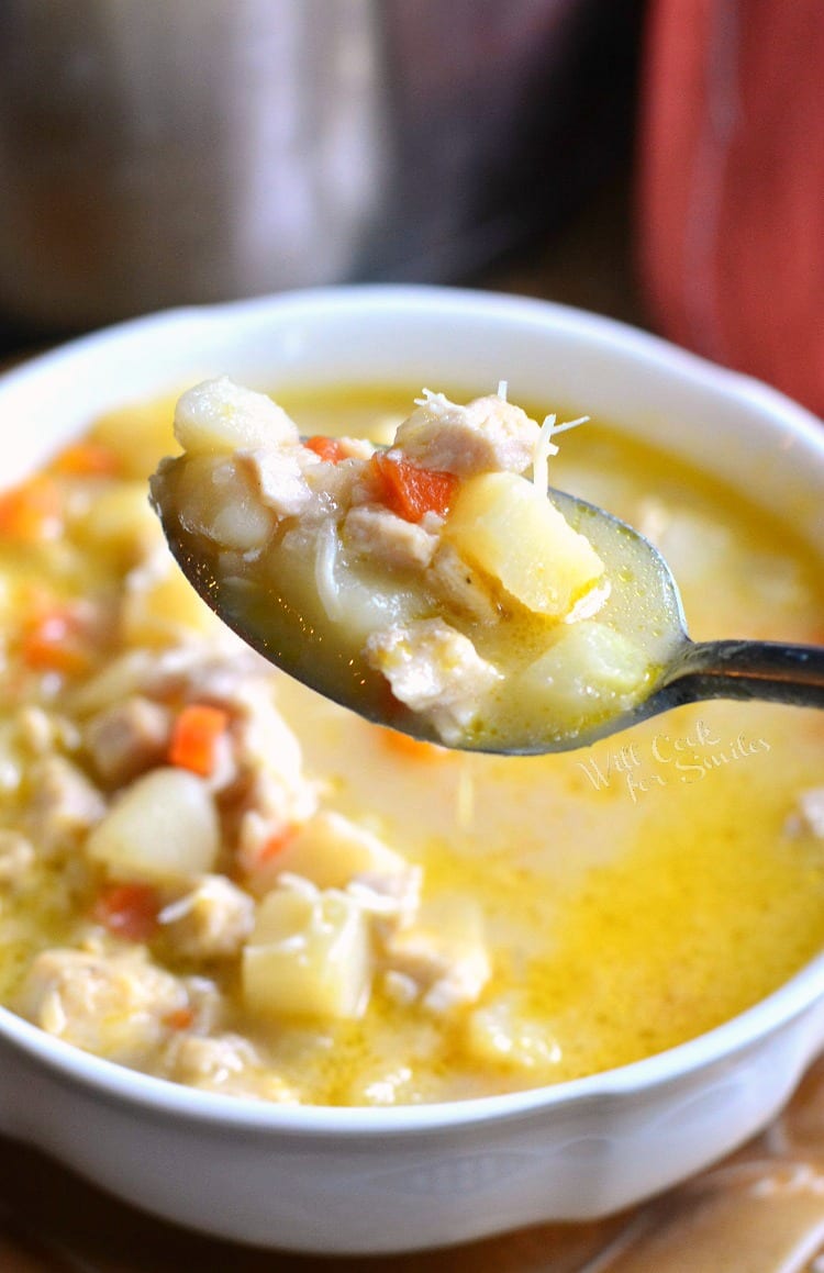 Creamy, Chunky Turkey Potato Soup with cheese on top with a spoon with soup on it that is on a brown plate