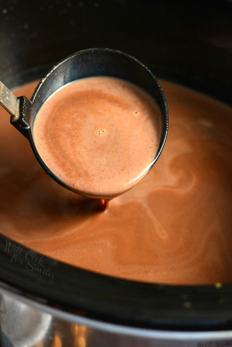 scooping ladle full of hot chocolate from a crock pot