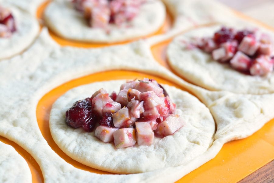 Turkey and Cranberry on the dough on a plastic orange cutting board 