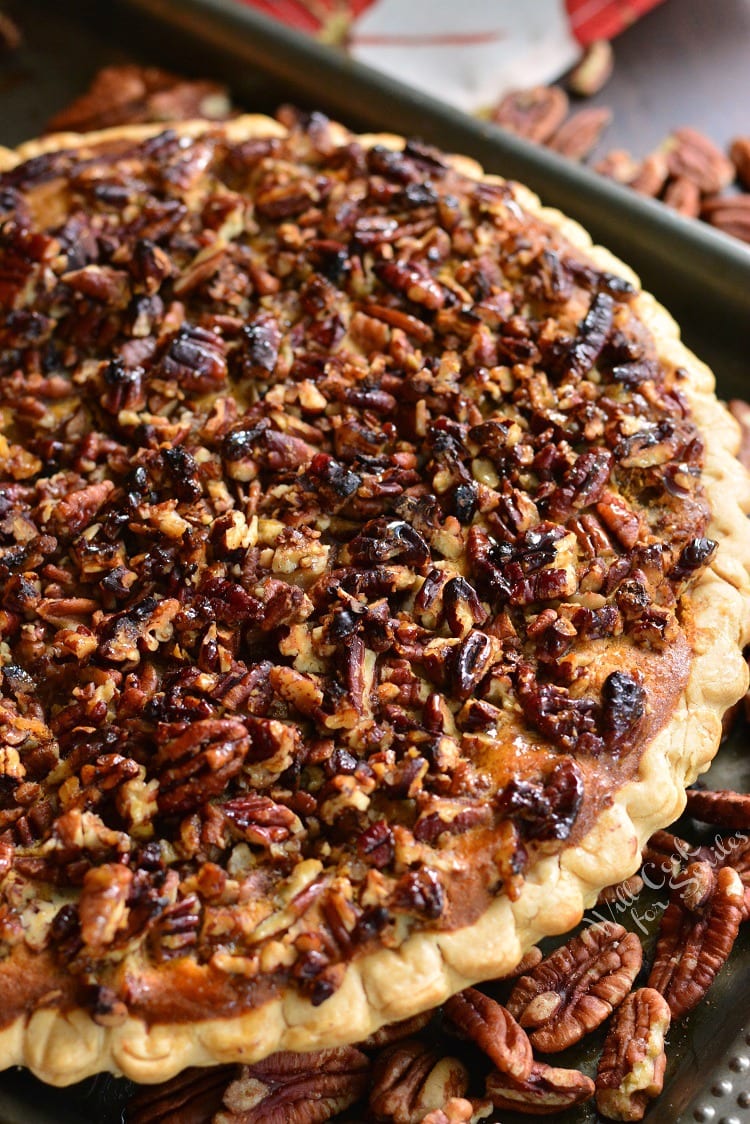 Pecan Crunch Sweet Potato Pie on a baking sheet with pecans all around it