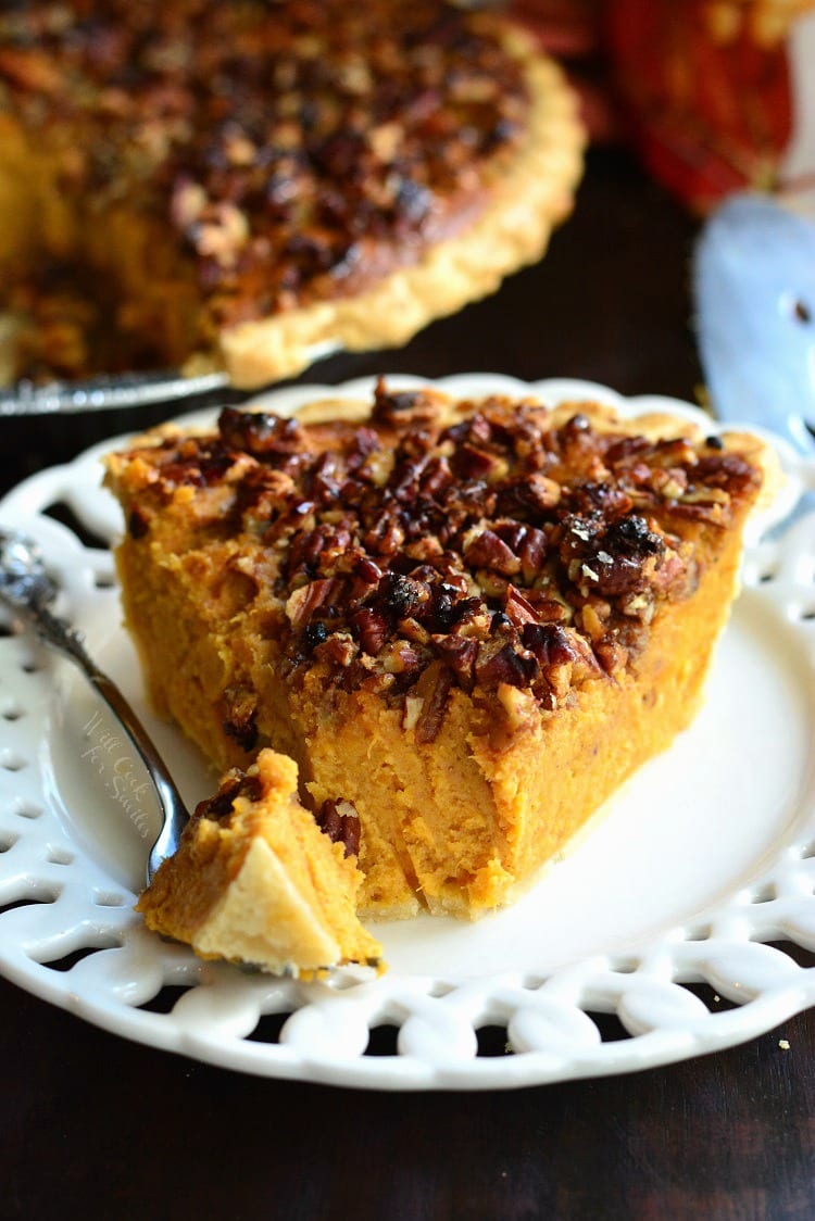 Pecan Crunch Sweet Potato Pie on a plate with a for with a bite on it the rest of the pie in the background 