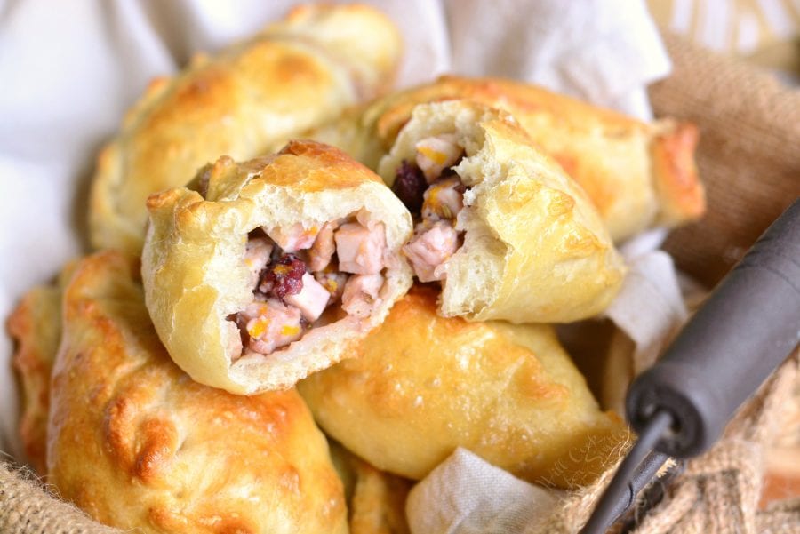 Turkey Cranberry Baked Piroshki cut in half in a basket with a dish cloth in the bottom 