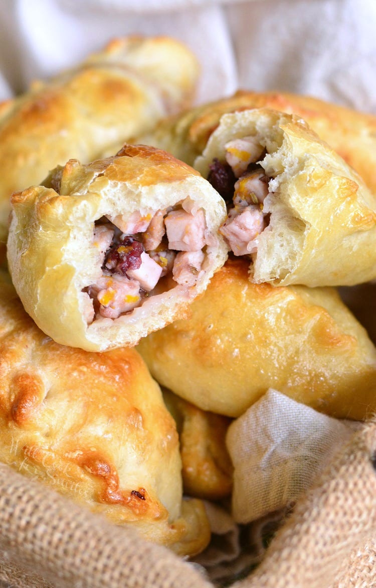 Turkey Cranberry Baked Piroshki cut in 2 in basket with a dish cloth in the bottom 