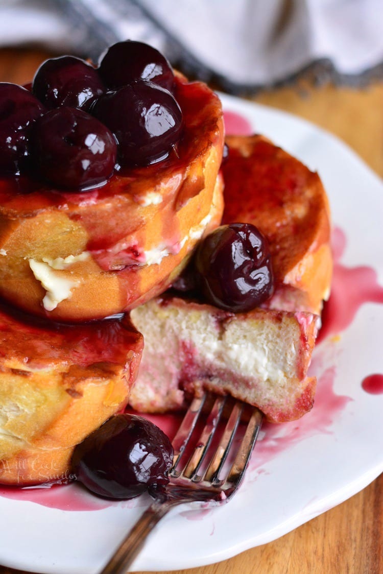 cherry french toast with a slice taken out and a fork on a plate.