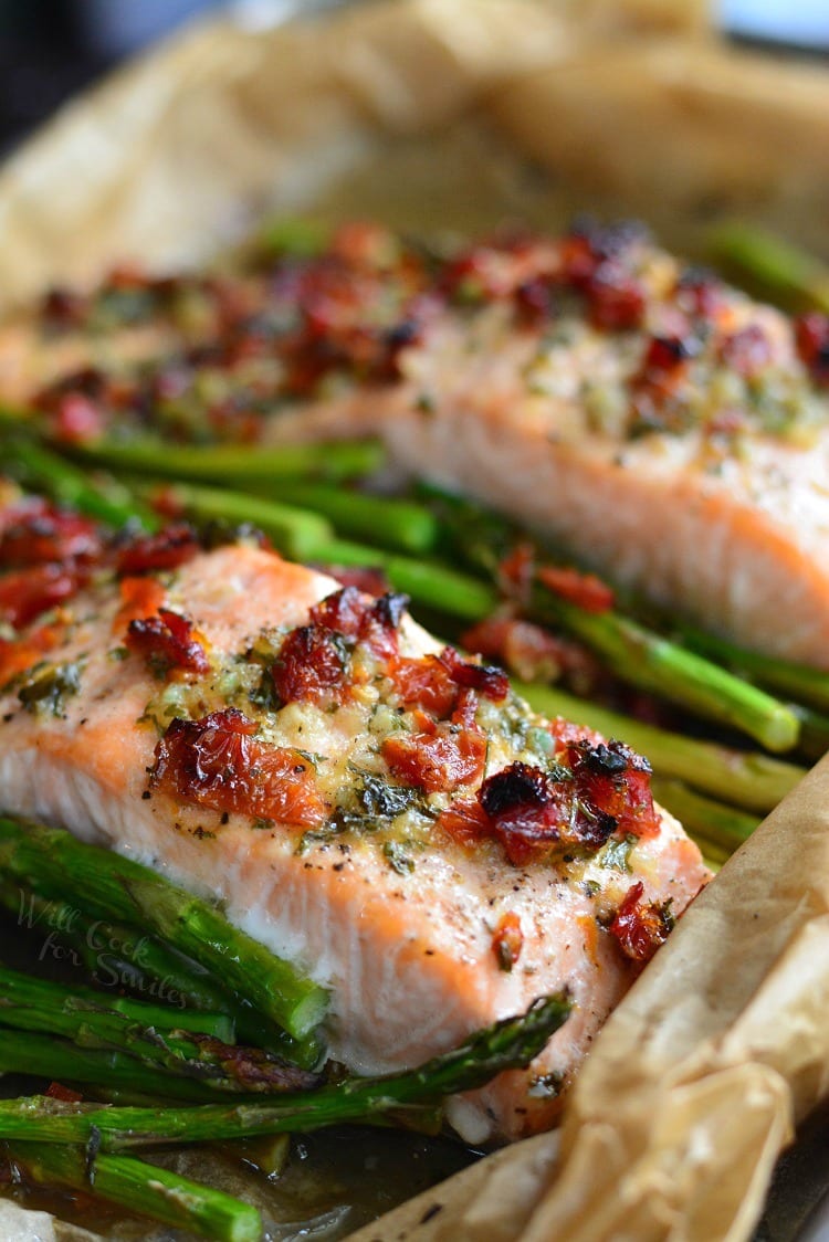 Sun Dried Tomato Lemon Baked Salmon and Asparagus in parchment paper on a baking sheet 