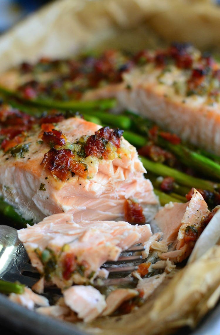 baked lemon and sun dried asparagus salmon on baking sheet flaked off with a fork.