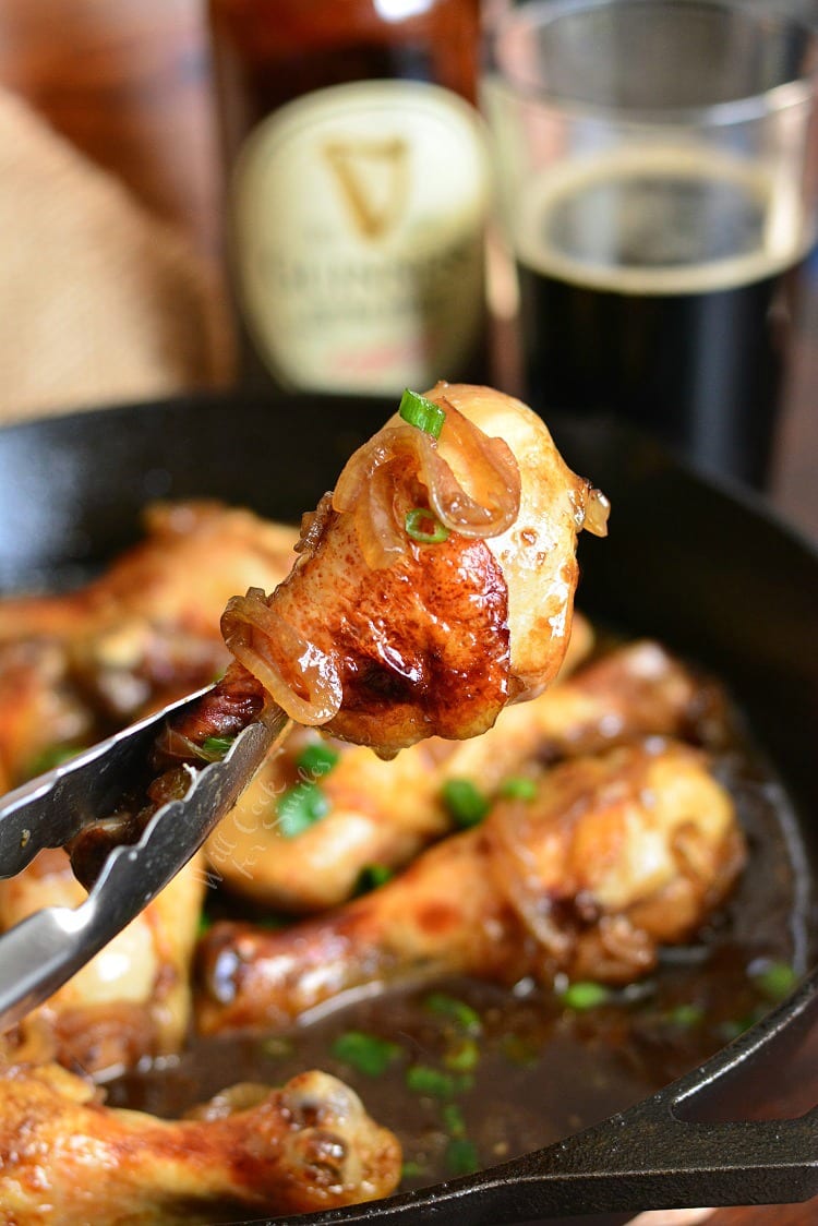Honey Guinness Chicken Drumsticks with tongs picking some up 
