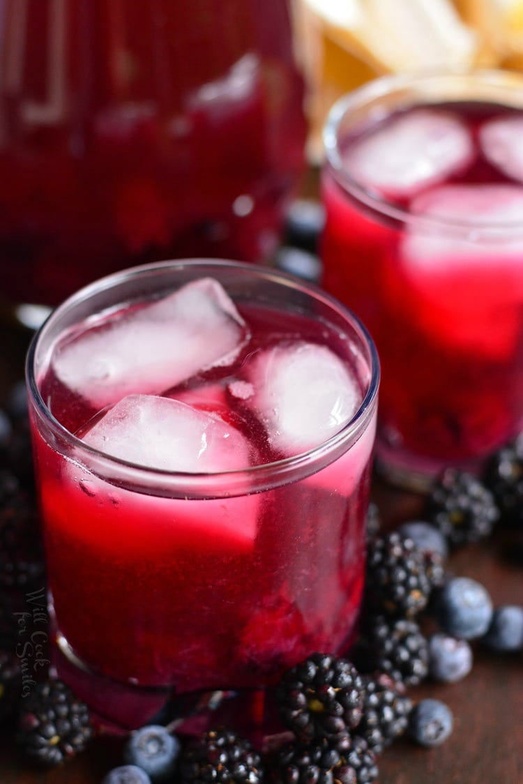 Blueberry Blackberry Iced Green Tea in glass with ice and blueberries and blackberries around it 