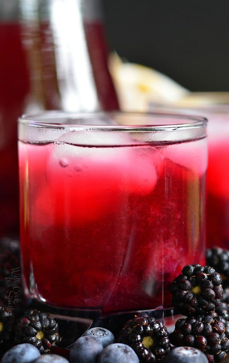 Blueberry Blackberry Iced Green Tea in glass with ice and blueberries and blackberries around it 