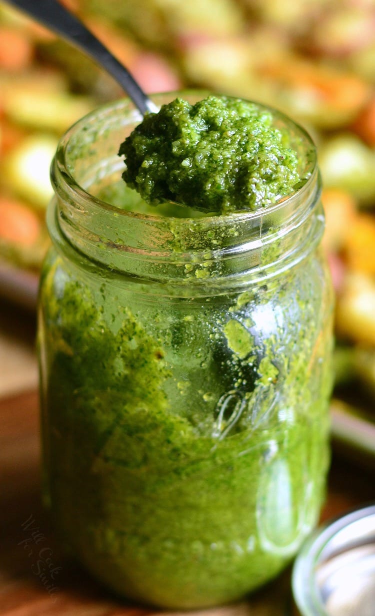 pesto in a jar with a spoon scooping some out 