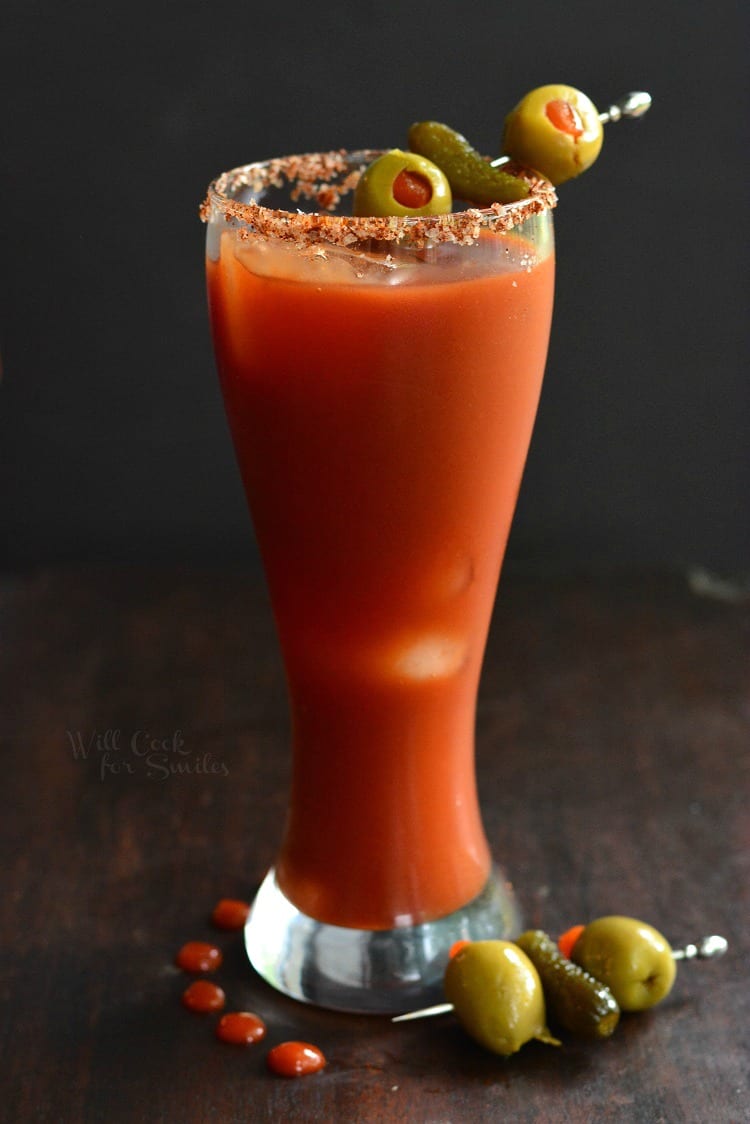 side video of bloody Mary in a glass with olive garnish in a glass and another on the table