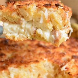 coconut bread pudding on a yellow casserole dish with a slice of pudding on a spatula.