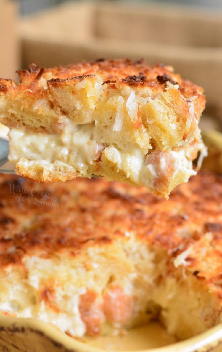 coconut bread pudding on a yellow casserole dish with a slice of pudding on a spatula.