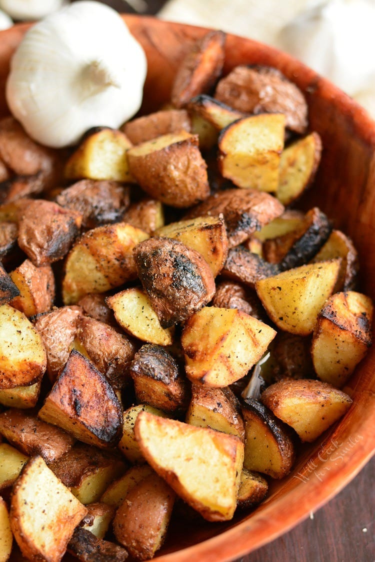 Grill Roasted Garlic Potatoes in a wood bowl with a bulb of garlic 