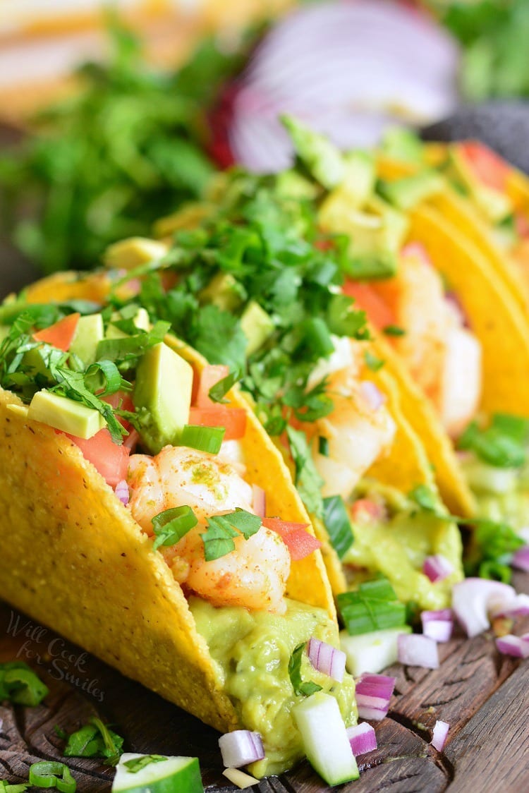  3 hard taco with guacamole, shrimp and cilantro and diced avocado on top. 