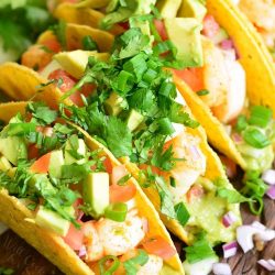 3 hard taco shells filled with shrimp, guacamole and avocados.